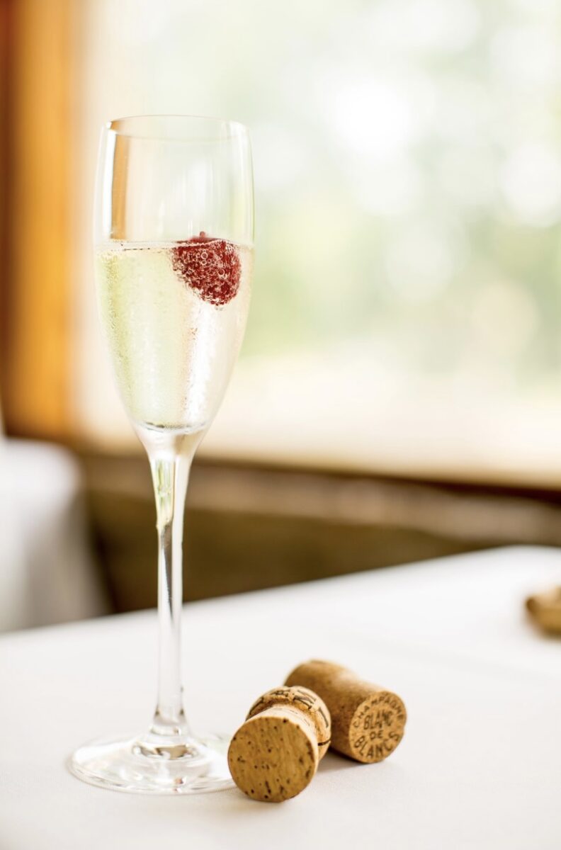 Sparkling wine with raspberry on table with corks