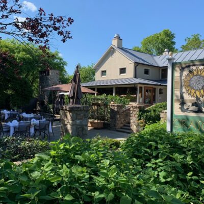 Patio seating in front of restaurant with sign and garden