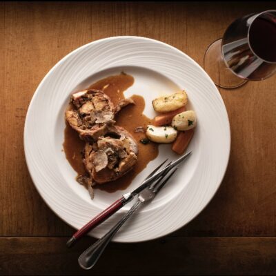 Roasted rabbit loin stuffed with chestnuts and mushrooms with shaved white truffle and a glass of wine