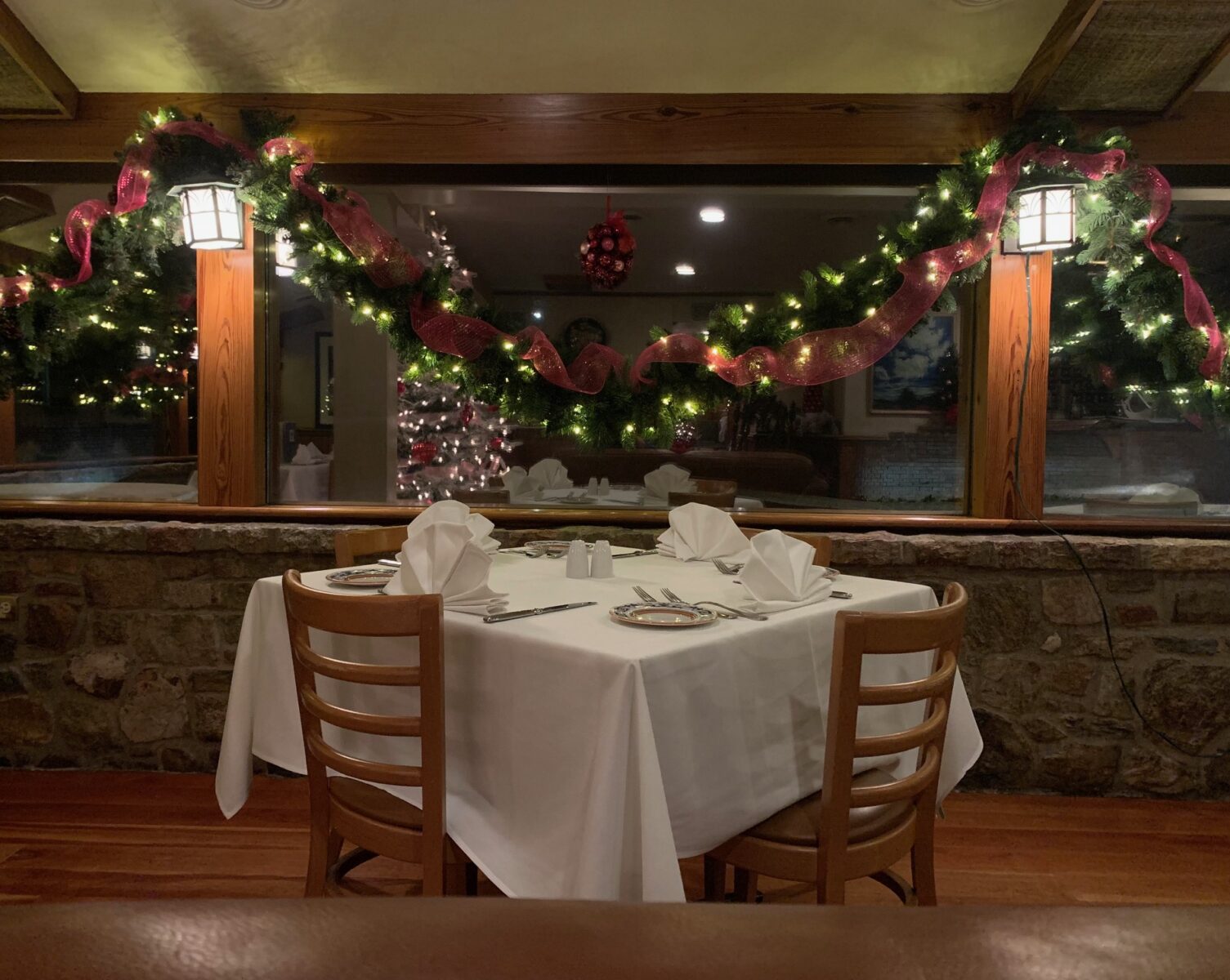 Set table with festive  windows adorned with garland and ribbon
