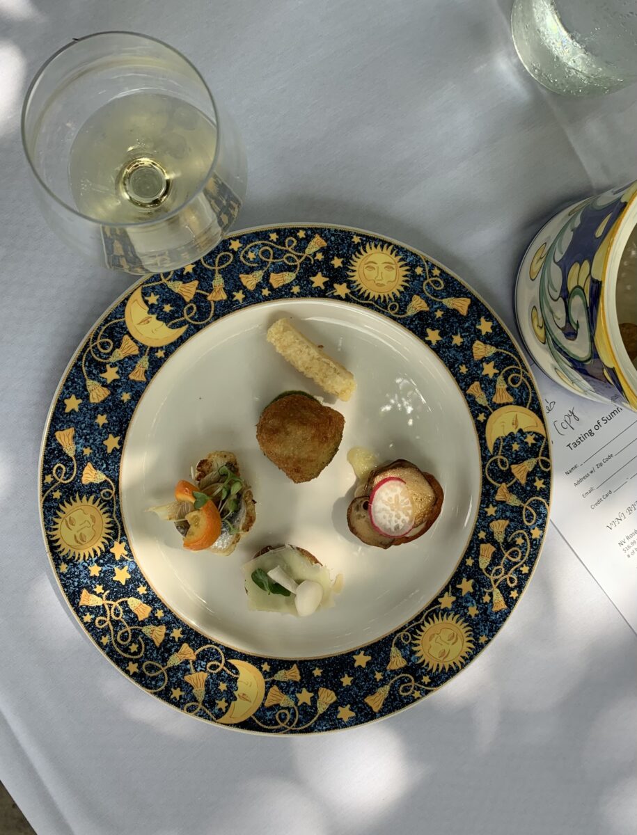 An assortment of small appetizers with a glass of white wine
